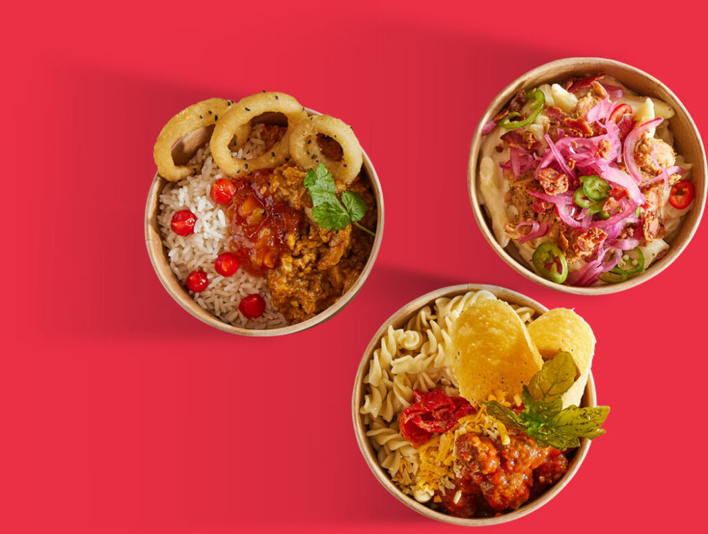 Selection of bowls with curry, pasta and burrito on a red background